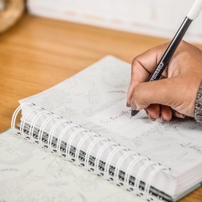 Hand writing in a notebook with a pen on a wooden surface