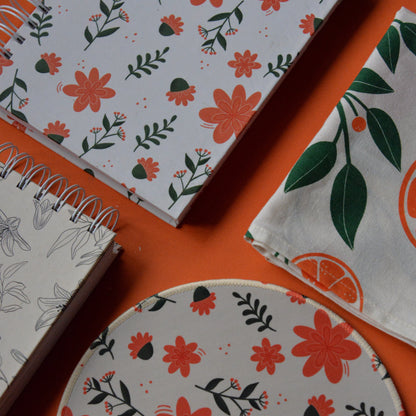 Floral-patterned notebooks and coasters on an orange surface