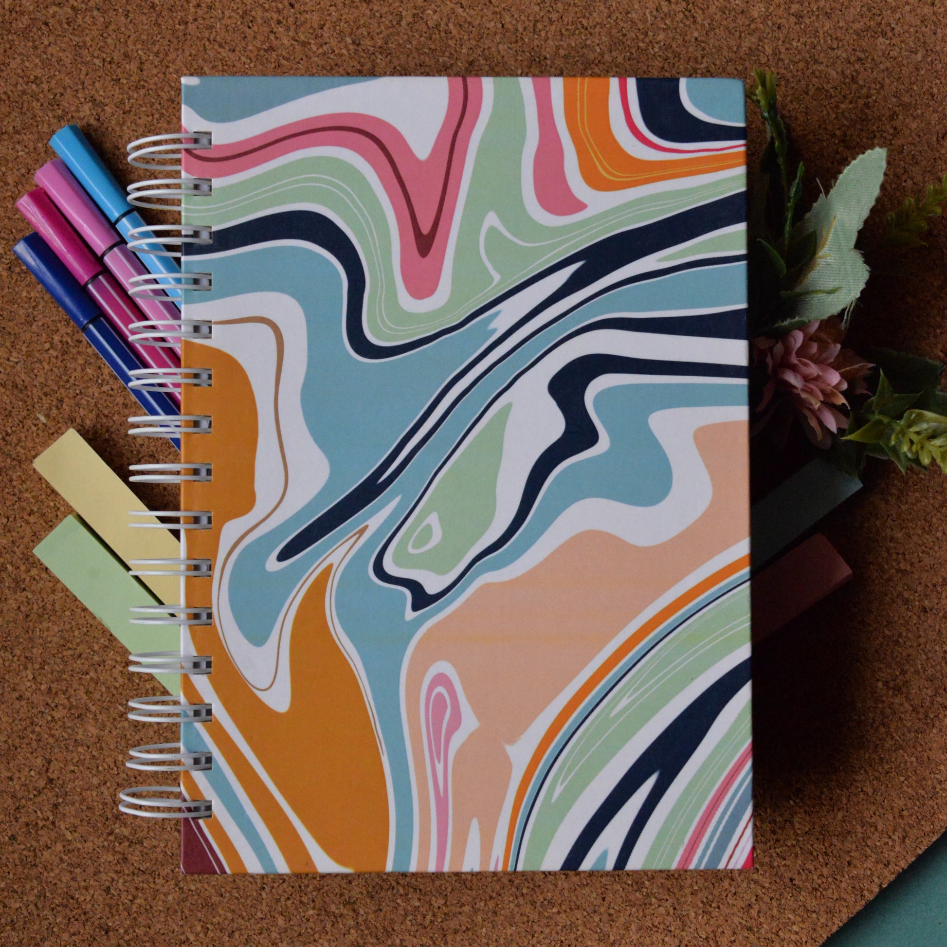 Notebook with colorful abstract design on a cork board