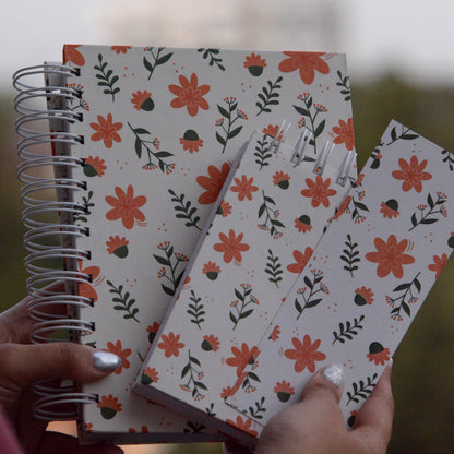 Floral-patterned notebooks held by a person with a blurred background